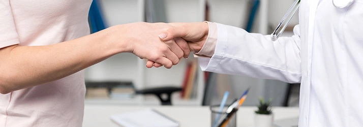 A close-up view of two people shaking hands in a healthcare setting