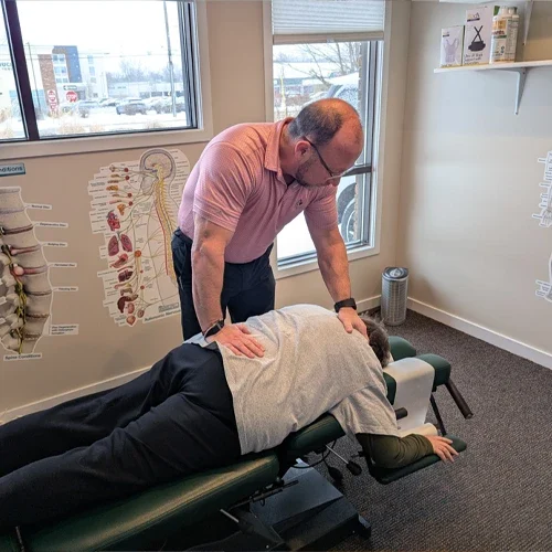 A clinical office setting with a person lying face down on a padded therapy table